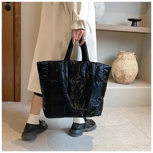 Detail of a large black quilted tote bag with FASHION patch and puffy padded handles