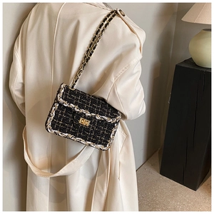 Vue détaillée d'un sac en tweed noir et crème avec chaîne dorée sur un trench-coat chic