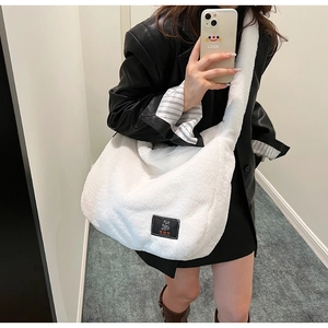 Détail d'un sac bandoulière blanc en peluche avec un écusson d'ours noir mignon