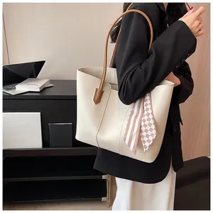 Detail of minimalist beige tote bag with chic silk scarf on brown handles for commute