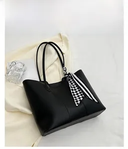 Top view of a minimalist black leather tote bag with a decorative silk scarf accessory