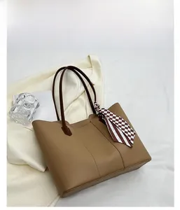 Detail of khaki tote bag featuring a checkered scarf accent and dark brown straps
