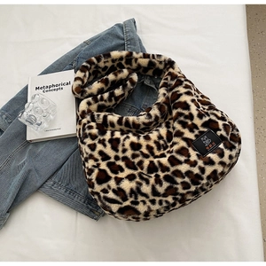 Sac à bandoulière en peluche léopard avec jean et livre sur fond blanc, vue à plat de dessus