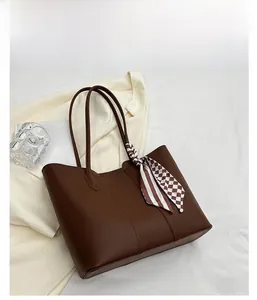 Detailed shot of brown leather tote bag with a checkered silk scarf on the handle