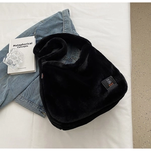 Détail du sac à bandoulière en fausse fourrure noire avec écusson d'ours et texture douce