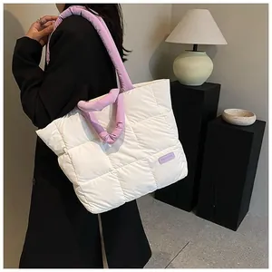Detail of white quilted tote bag featuring plush texture and purple round handles