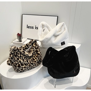 Gros plan de sacs cabas en fausse fourrure léopard, blanc et noir sur un présentoir