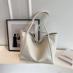 Minimalist beige pebble leather tote bag with slim shoulder straps and metal closure