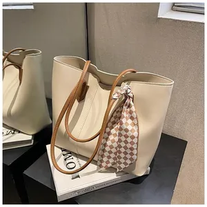 Detail of minimalist tote bag with textured faux leather and decorative plaid scarf