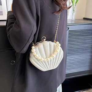 Sparkling shell evening bag with large pearl handle and gold chain strap on model