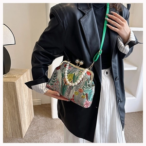 Detailaufnahme der Retro-Blumentasche mit Perlenkette und grünem Schultergurt