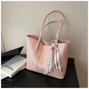 Detail of light pink leather tote bag featuring a decorative checkered silk scarf on handle