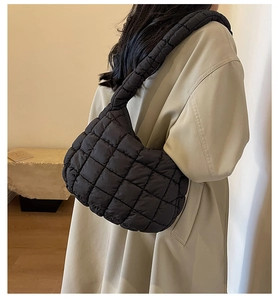 Detail of black quilted cloud bag showing the puffy nylon texture and wide padded strap