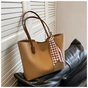 Detail of khaki tote bag with dark brown handles and checkered decorative silk scarf