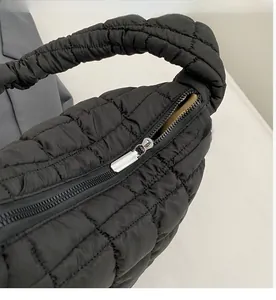 Close-up detail of the smooth zipper closure and quilted puffer fabric on this black bag