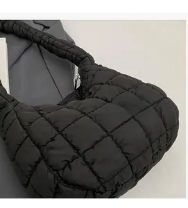 Detail of black quilted puffer bag with glossy nylon texture and square stitching patterns