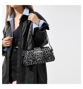 Detail of leopard print baguette bag with silver buckle worn by a model in studio