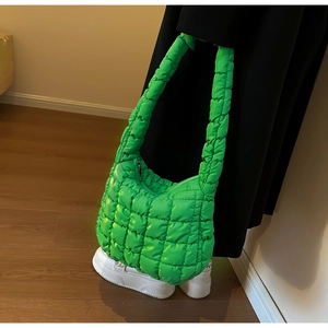 Detail of green quilted puffer crossbody bag with metallic zipper and textured fabric