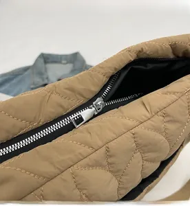 Close-up of smooth metal zipper and quilted rhombus texture on khaki puffer tote bag