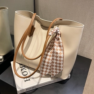Minimalist off-white tote bag with brown leather straps and decorative plaid scarf