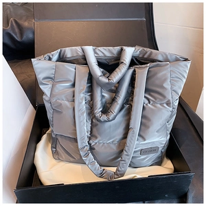 Detail van donkergrijze gewatteerde puffer tote bag met metaalglans en modelabel