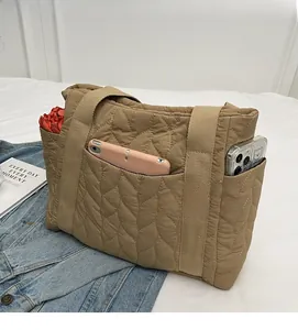 Detailed shot of khaki quilted tote bag showing practical side pockets and large capacity