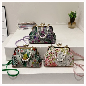 Nahaufnahme von drei Vintage-Bügelaschen mit Perlenhenkeln und floralen Muschelmustern
