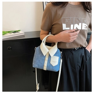 Detail van lichtblauwe denim crossbodytas met wit leer en ontwerp met een hemdkraagflap