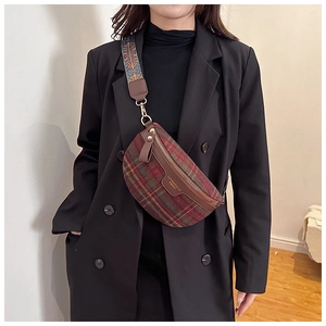 Détail du sac à carreaux rouge et vert en laine avec zip doré et bandoulière tissée