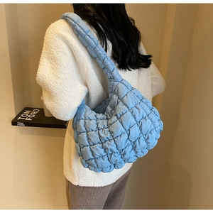 Close-up of light blue quilted cloud bag showing puffed fabric and wide shoulder strap