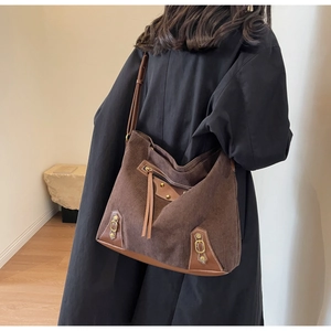 Close-up of brown corduroy tote bag with leather trim and fringe tassel detail