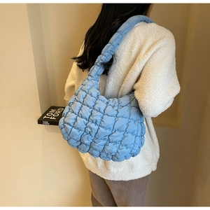 Detail of light blue quilted cloud bag with padded texture and wide shoulder strap
