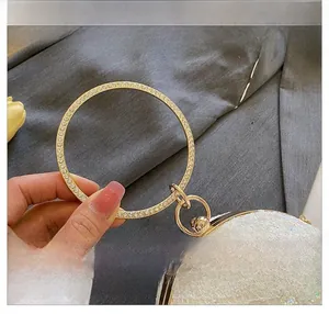 Detail des eleganten goldenen Rundgriffs und der weißen Paillettenstruktur der Abendtasche