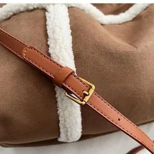 Detail of adjustable leather strap and vintage gold buckle on brown suede tote bag