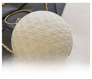 Detailansicht einer kugelrunden Abendtasche mit weißen Pailletten und goldenem Metallgriff