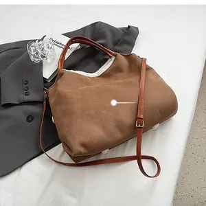 Rear view of brown suede tote bag with white shearling trim and adjustable strap