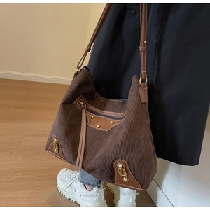 Detail of dark brown corduroy tote bag with golden rivets and leather fringe tassels