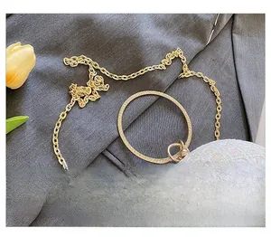 Detailaufnahme der goldenen Metallkette und funkelnden runden Abendtasche mit Perleneffekt