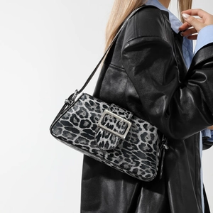 Leopard print underarm shoulder bag with silver buckle and black leather strap worn by a model