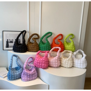 Multiple colors of quilted puffer bags displayed on minimalist white showroom pedestals