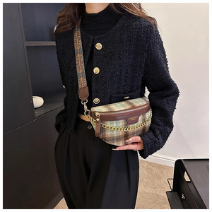 Détail du sac bandoulière à carreaux verts avec chaîne dorée et sangle tissée