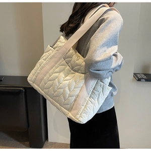 Detailed side view of large quilted puffer tote bag in cream finish with leaf pattern