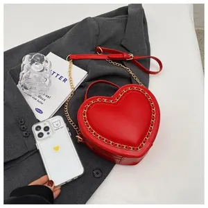 Detail of red heart shaped bag with gold chain edge decoration and smooth PU finish