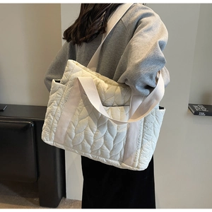 Detail of leaf-quilted pattern on off-white puffy tote bag with wide canvas strap