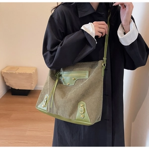 Detail of olive green corduroy tote bag with metallic studs and long tassel zippers
