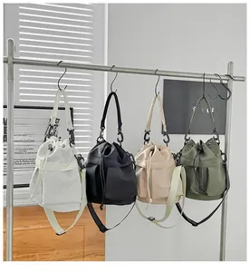 Detail of four nylon bucket bags in white, black, beige and olive green with drawstring