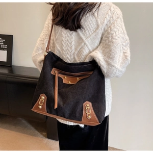 Detail of black corduroy tote with brown leather trim and golden horseshoe buckle