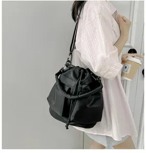 Detail of black nylon drawstring bucket bag with thick handle and adjustable strap