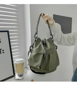 Detail of army green nylon bucket bag featuring a drawstring closure and tactical buckle strap