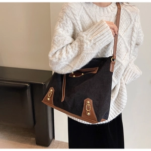 Detail of vintage corduroy tote bag with leather straps and retro bronze metal hardware